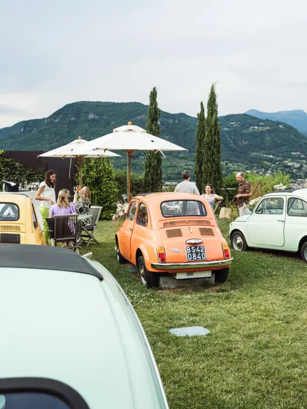 Eine Gruppe von Menschen sitzt um ein klassisches Auto im Freien.