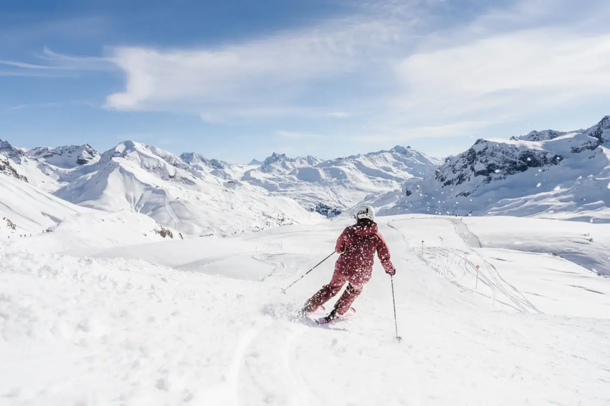 Eine Person fährt auf Skiern einen schneebedeckten Berg hinunter.