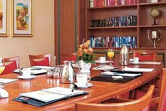 Ein Tisch mit einem Bücherregal und einer Vase mit Orangensaft.