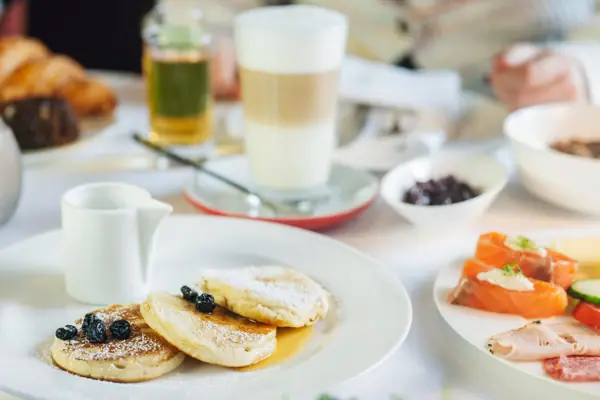 Ein Teller mit Pfannkuchen, garniert mit Heidelbeeren und Puderzucker.
