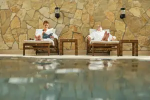 Ein Mann und eine Frau sitzen auf Liegestühlen am Pool.