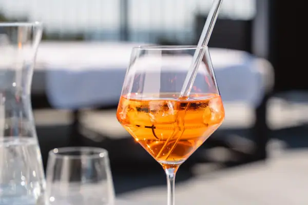 Ein Glas mit orangener Flüssigkeit und Eis auf einem Tisch.