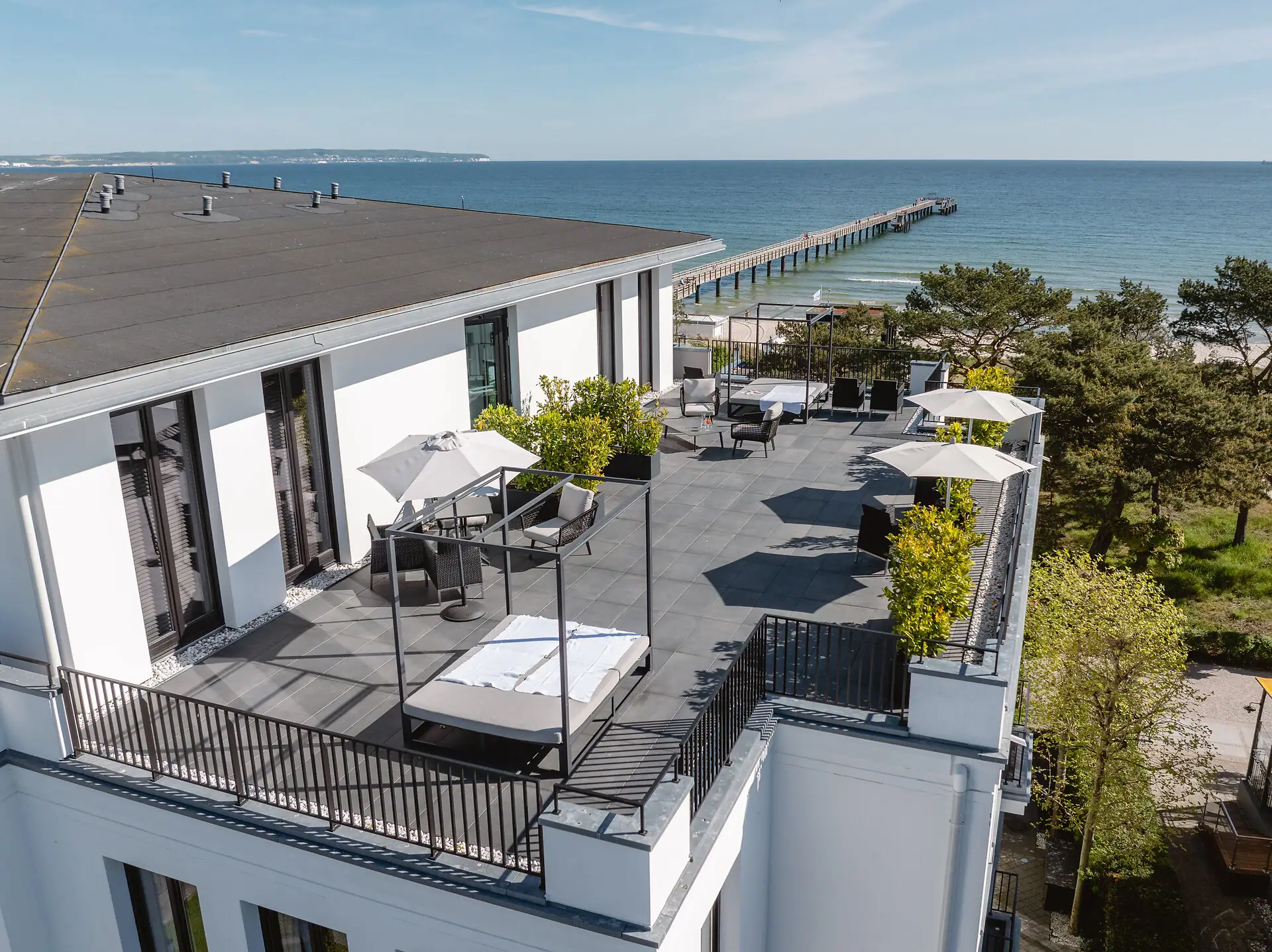 Ein Gebäude mit einer Terrasse und Sonnenschirmen mit Blick auf das Wasser.