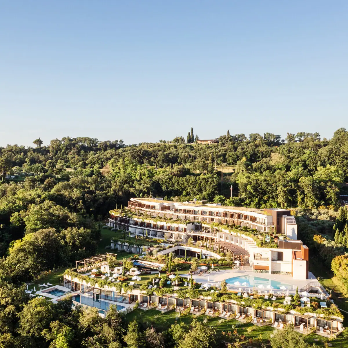 A-ROSA Gardasee Resort inmitten der grünen Hügellandschaft mit Pools, Sonnenterrassen und Panoramablick über Italien.