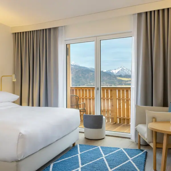 Hotelzimmer mit Bett, Teppich und Sessel.