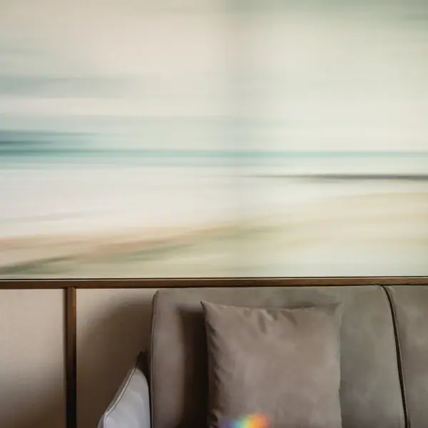 Couch mit Kissen vor einem unscharfen Strandbild an der Wand.