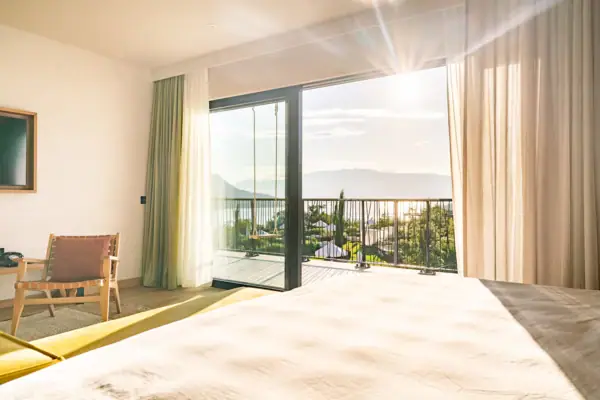 Ein Zimmer mit einem Bett und einem Balkon mit Blick auf das Meer.