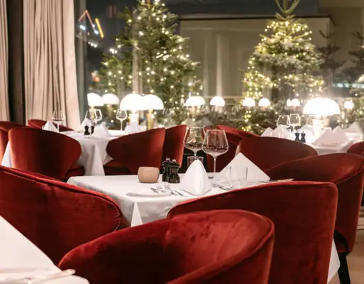 Ein Tisch mit roten Stühlen und weißer Tischdecke.