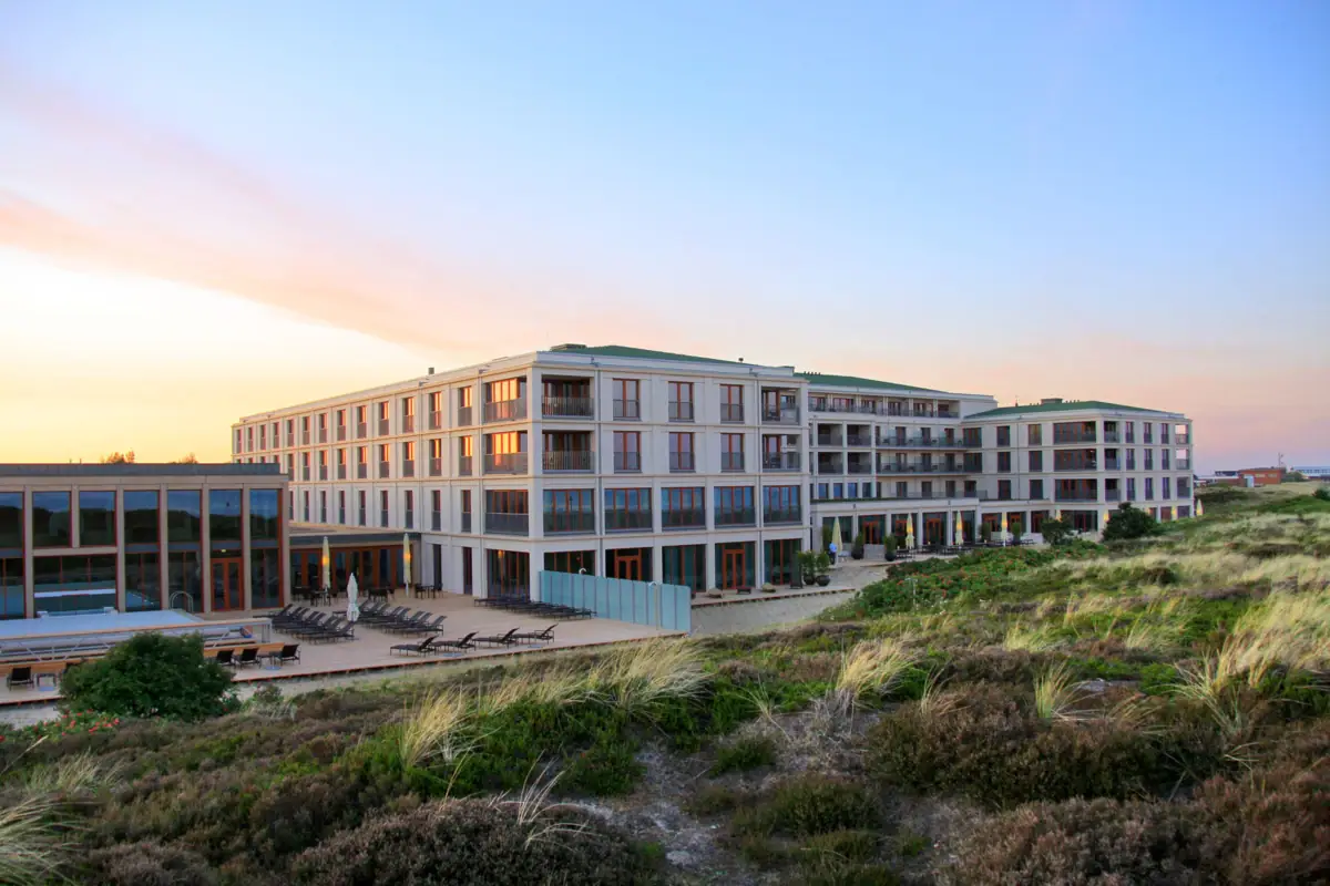 Das A-ROSA Hotel Sylt mit Rasen und Stühlen im Freien.