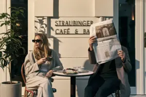 Ein Mann und eine Frau sitzen an einem Tisch und lesen eine Zeitung.