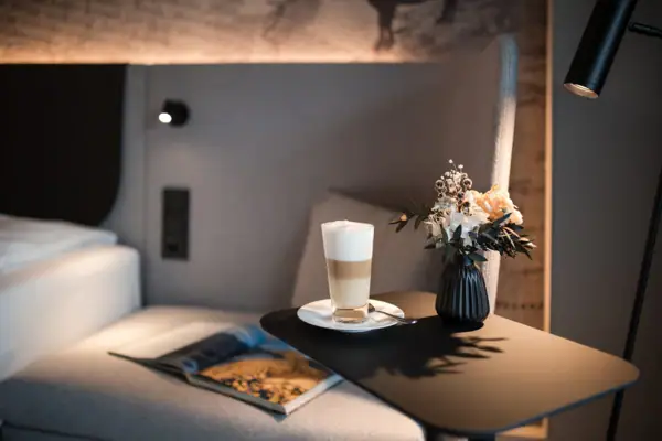 Ein Tisch mit einem Getränk und einer Vase mit Blumen darauf.