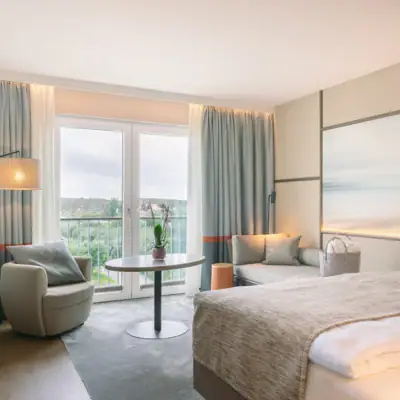 Zimmer im A-ROSA Hotel Sylt mit Bett, Tisch und Stühlen.