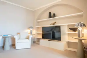 Wohnzimmer mit Fernseher und Regalen.