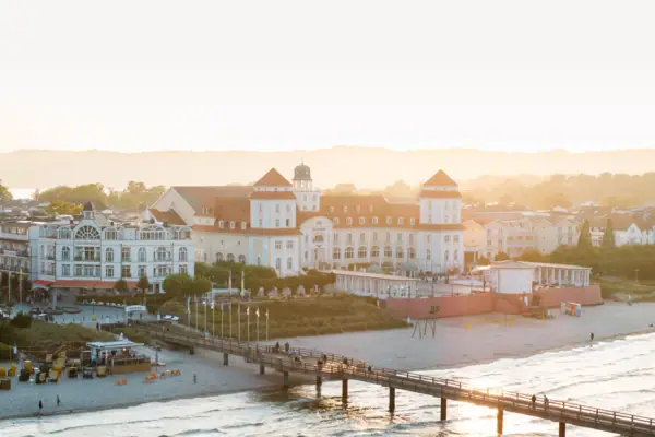 Ein Pier über einem Strand mit Gebäuden und Wasser im Hintergrund.