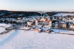 Schneebedeckte Stadt mit Gebäuden und einem Gewässer im Winter.