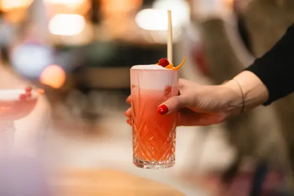 Eine Hand hält ein Glas mit einem Getränk in der Bar im A-ROSA Hotel Sylt.