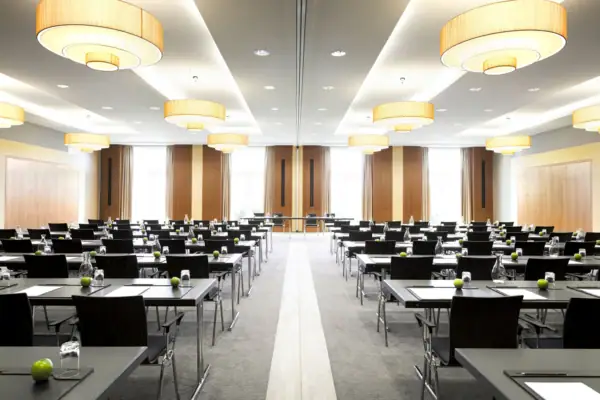 Ein Veranstaltungsraum mit Tischen und Stühlen in Parlament Bestuhlung.