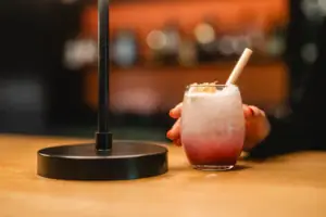 Eine Hand hält ein Getränk mit Trinkhalm und Cocktailgarnitur.