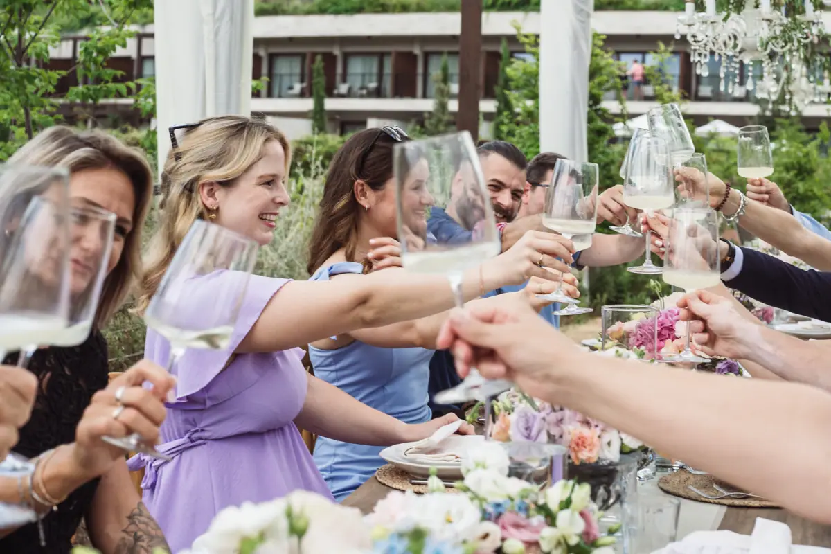 Gäste stoßen bei einer privaten Feier im Garten des A-ROSA Gardasee mit Sektgläsern an, umgeben von festlich dekorierten Tischen.