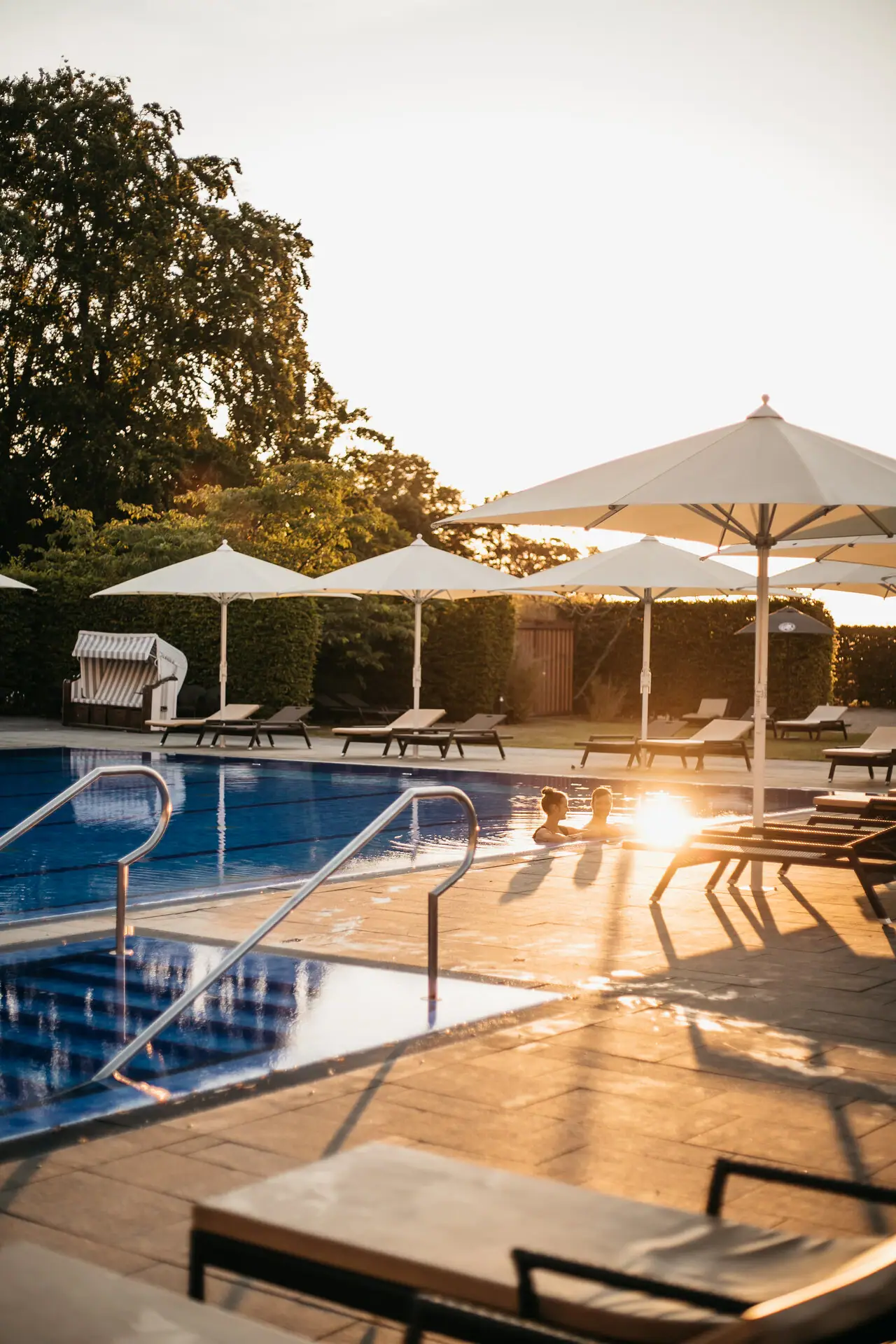 Ein Außenpool mit Sonnenschirmen und Liegestühlen.