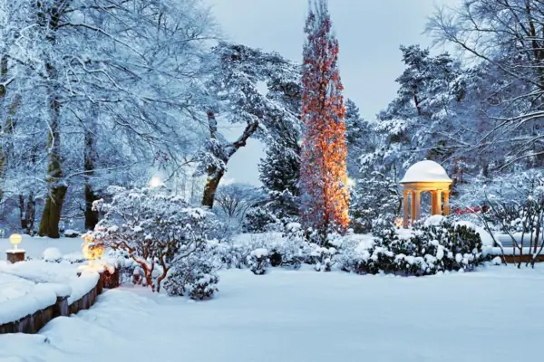Ein verschneiter Park mit einem Pavillon und Bäumen.