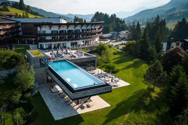 Ein Außenpool in einem Hotel, umgeben von Bäumen und einem klaren Himmel.