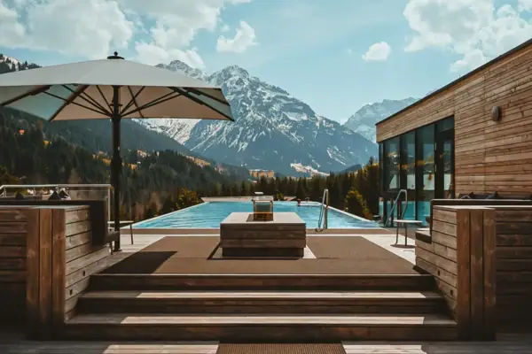 Ein Pool mit Holzdeck und großem Sonnenschirm.