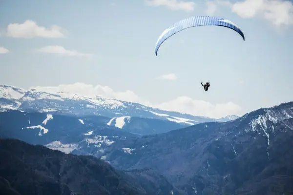 Eine Person fliegt mit einem Fallschirm über Berge.