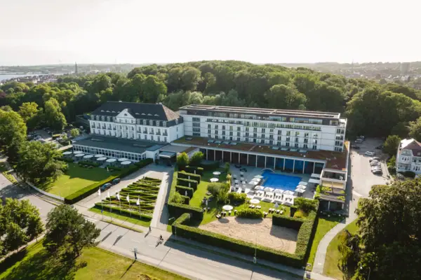 Das große weiße Kurhaus Gebäude mit einem Pool und Bäumen.