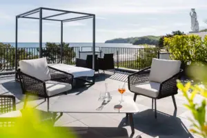 Eine Terrasse mit Stühlen und einem Tisch auf einem Deck mit Blick auf das Meer.