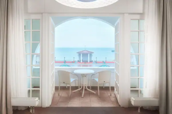 Ein Zimmer mit einem Tisch und Stühlen, das einen Blick auf das Meer bietet.