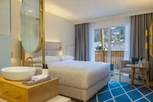 Schlafzimmer mit großem Bett, Stuhl und großem Spiegel.