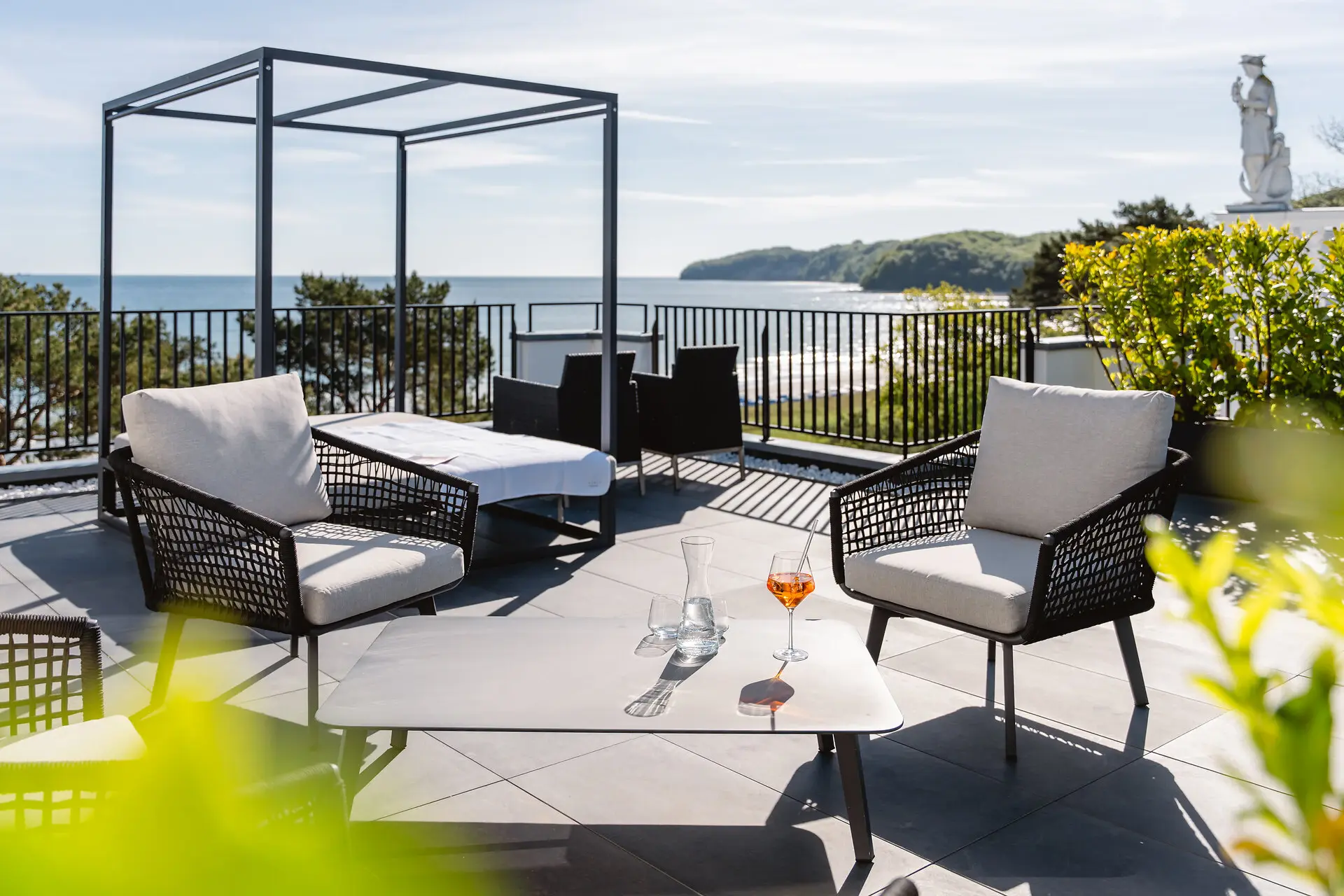 Eine Terrasse mit Stühlen und einem Tisch auf einem Deck mit Blick auf das Meer.