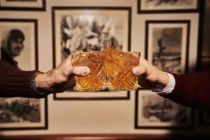 Zwei Hände halten Gläser mit spritzender Flüssigkeit.