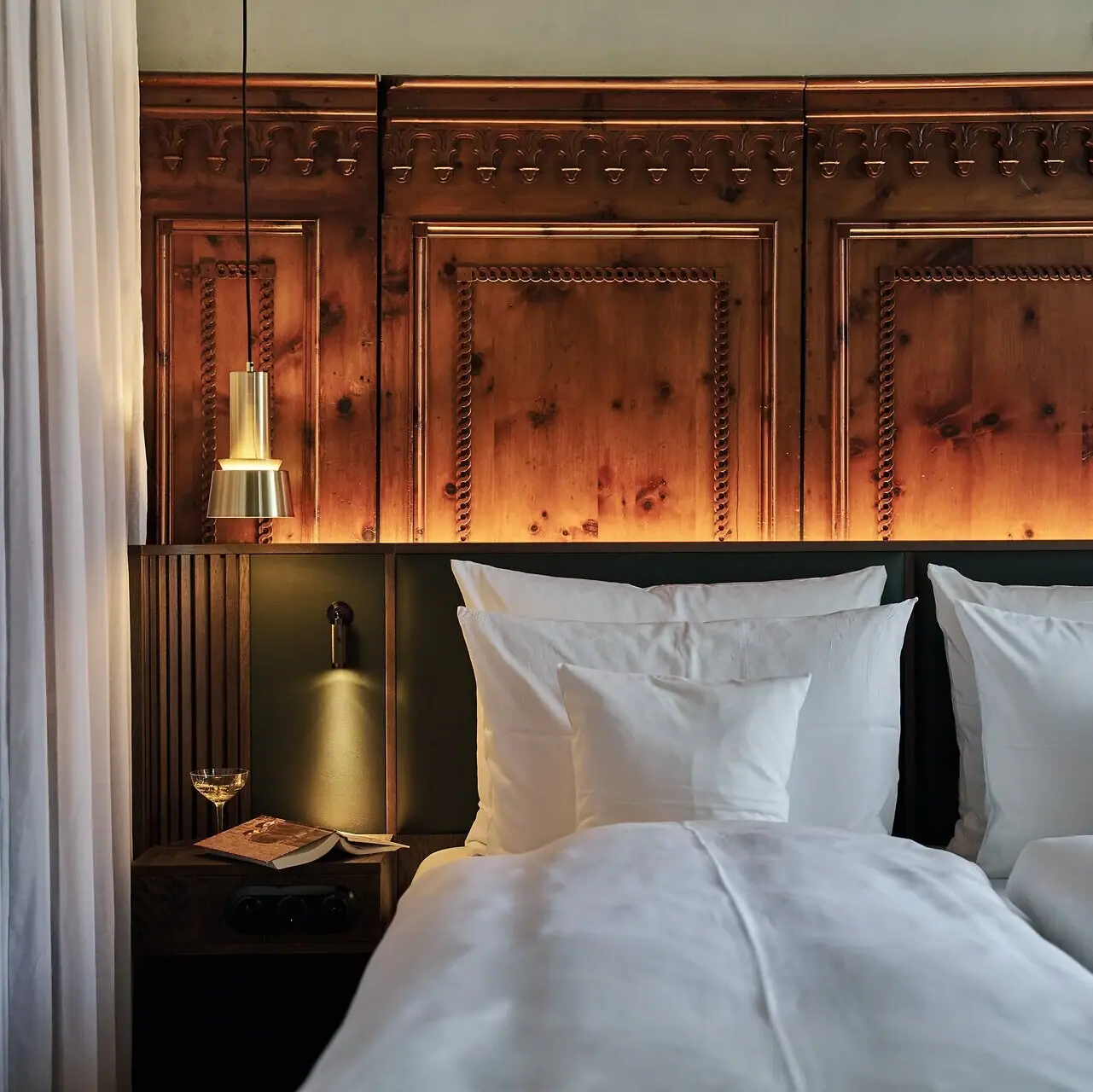 Ein Bett mit weißen Kissen und einer Lampe an der Seite.