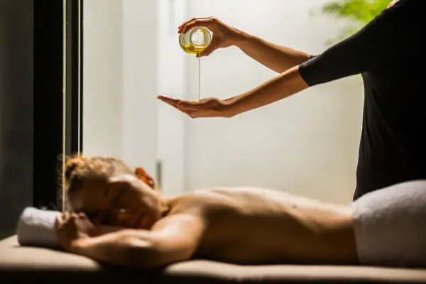 Vinotherapie Eine Person gießt Öl in die Hand einer anderen Person.