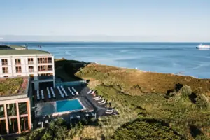 Ein Außenpool vor einem Gebäude mit Blick auf das Meer im Hintergrund.