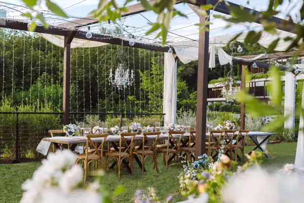 Ein für eine Feier langer, gedeckter Tisch im Garten vom Hotel. Der Tisch ist festlich gedeckt und mit Blumen geschmückt.