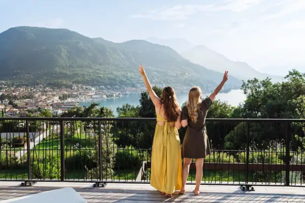 Zwei Frauen stehen auf einem Deck mit Blick auf einen See und Berge.