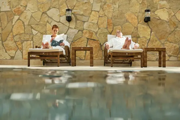 Ein Mann und eine Frau sitzen auf Liegestühlen am Pool.