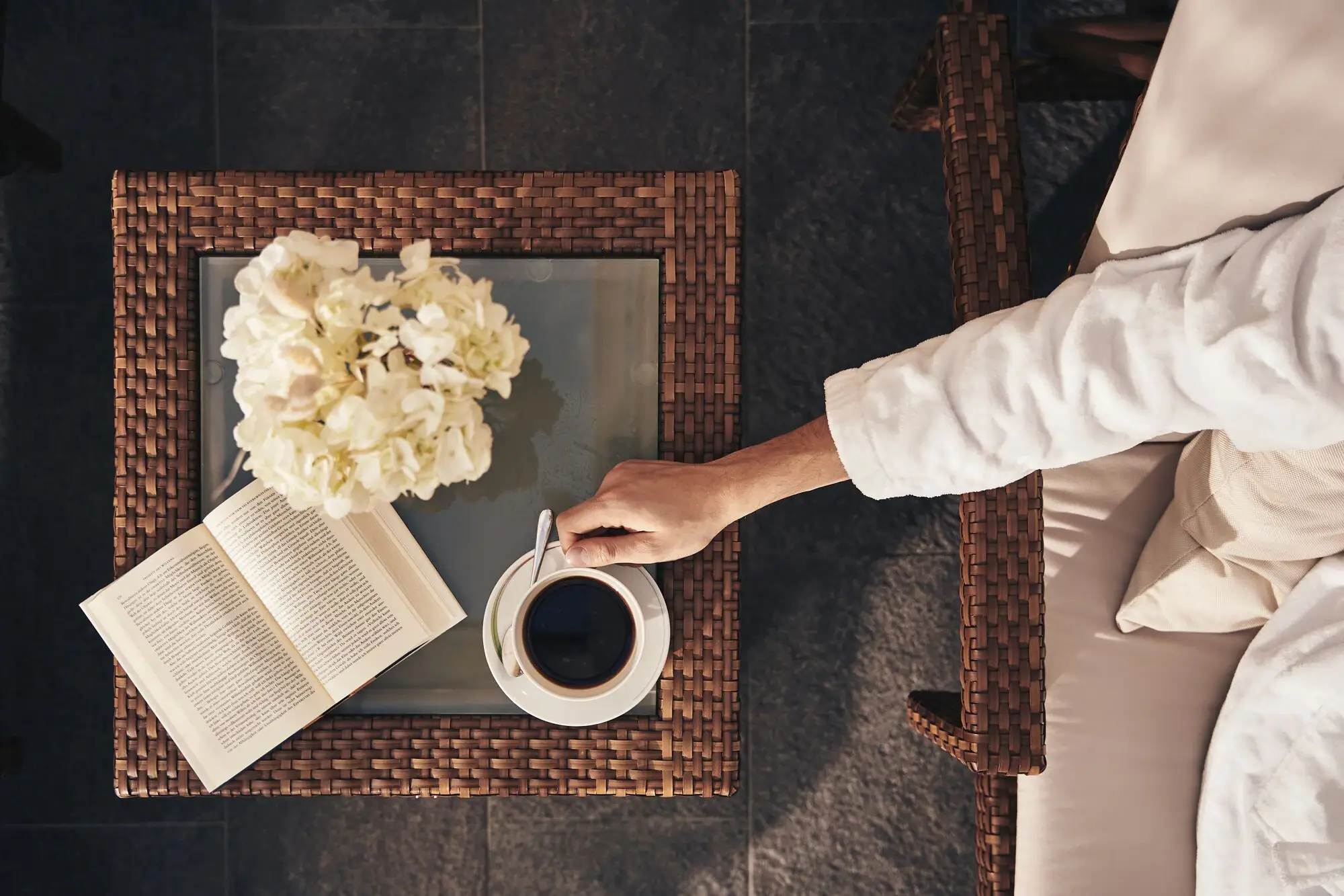 Eine Person hält eine Tasse Kaffee und ein Buch.