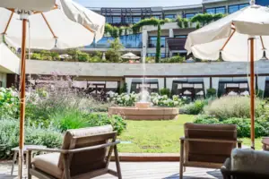Stühle und Sonnenschirme in einem Innenhof mit einem Brunnen im Hintergrund