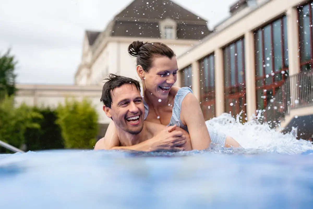 Ein Mann trägt eine Frau in einem Pool.