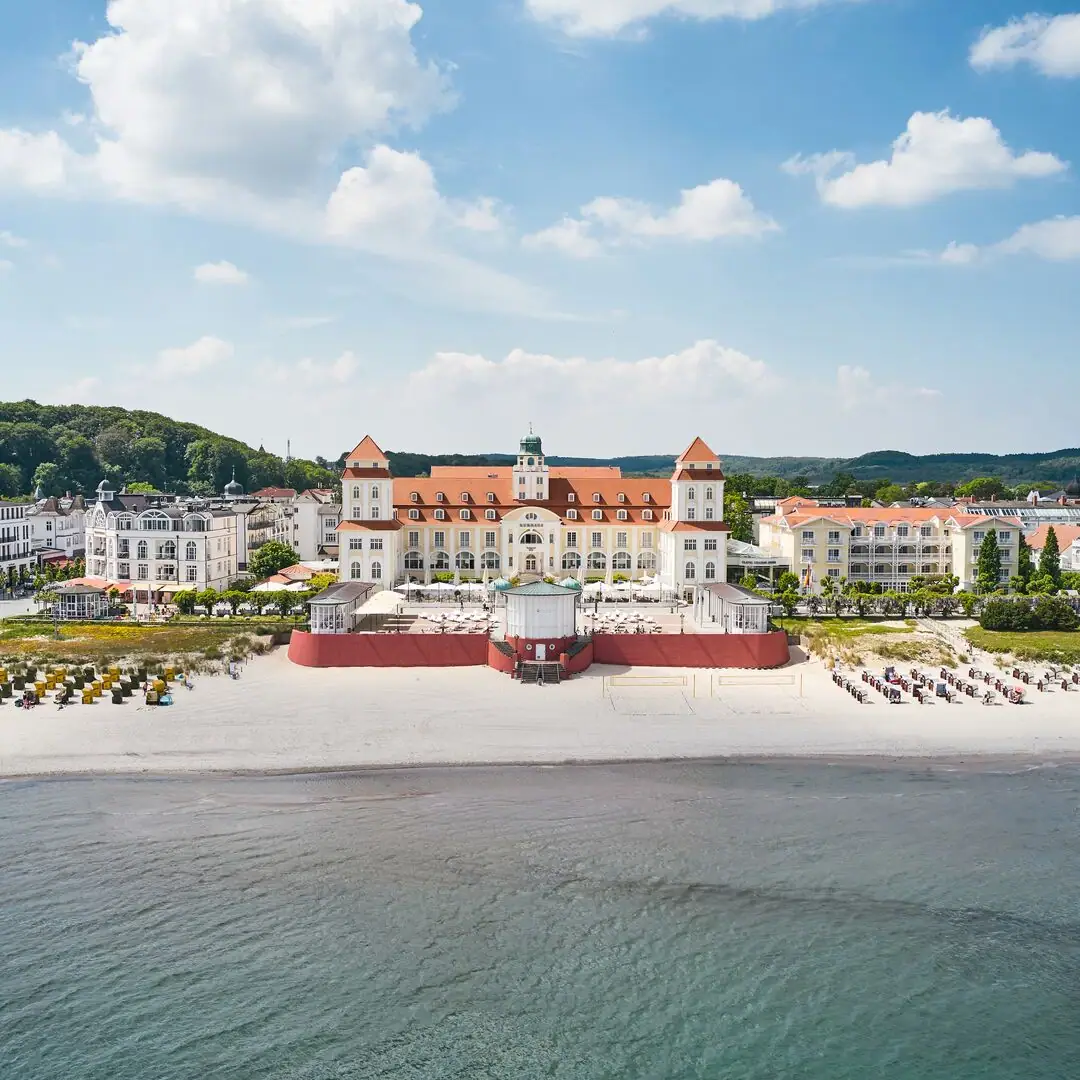 Großes Gebäude am Strand mit einem Gewässer im Vordergrund.