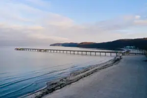 Langer Steg am Strand mit Blick auf das Wasser und den Himmel.
