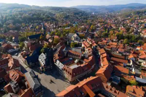 Luftaufnahme einer Stadt mit Häusern, Bäumen und Bergen im Hintergrund.