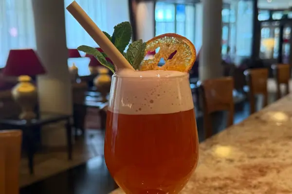 Ein Glas mit einem Strohhalm und einer Orangenscheibe darauf.