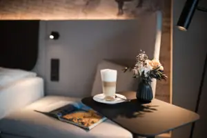 Ein Tisch mit einem Getränk und einer Vase mit Blumen darauf.
