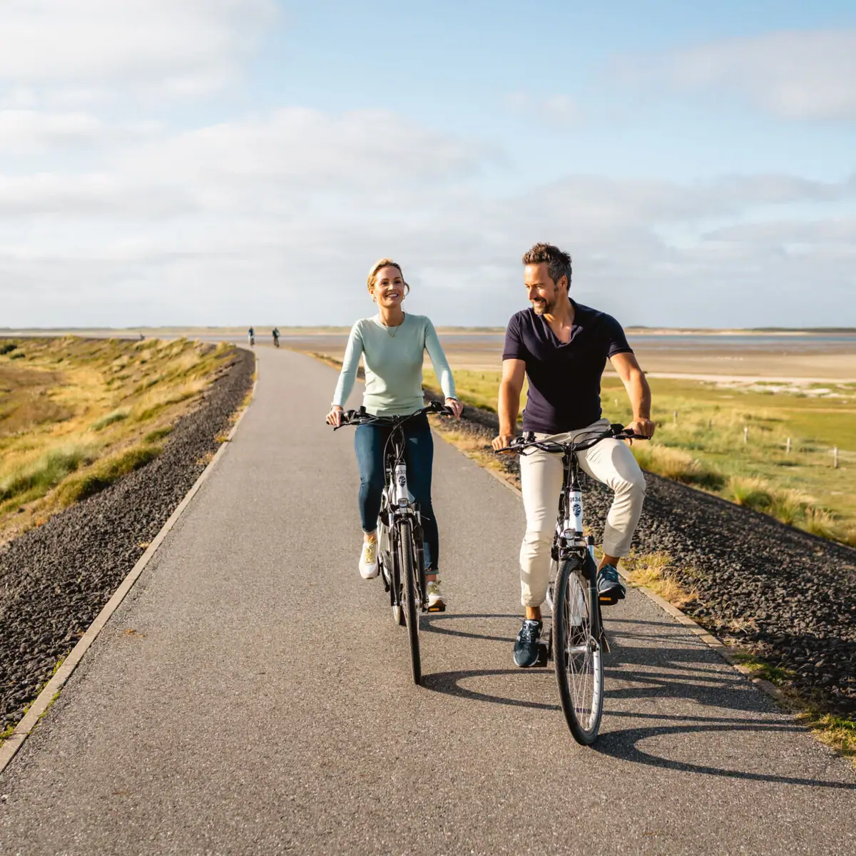 Ein Mann und eine Frau fahren auf einer Straße Fahrrad auf Sylt.
