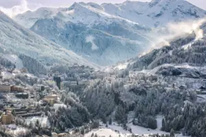 Verschneiter Berg mit Gebäuden und Bäumen.